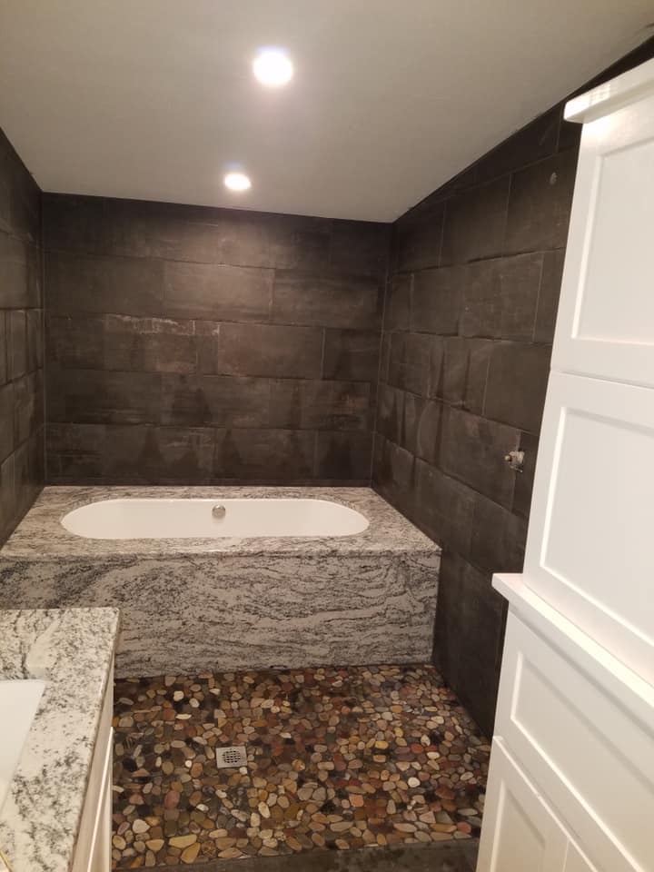 Dark marble tile bath with river-rock shower floor installed in Brady TX — bathroom tile by Heart of Texas Flooring
